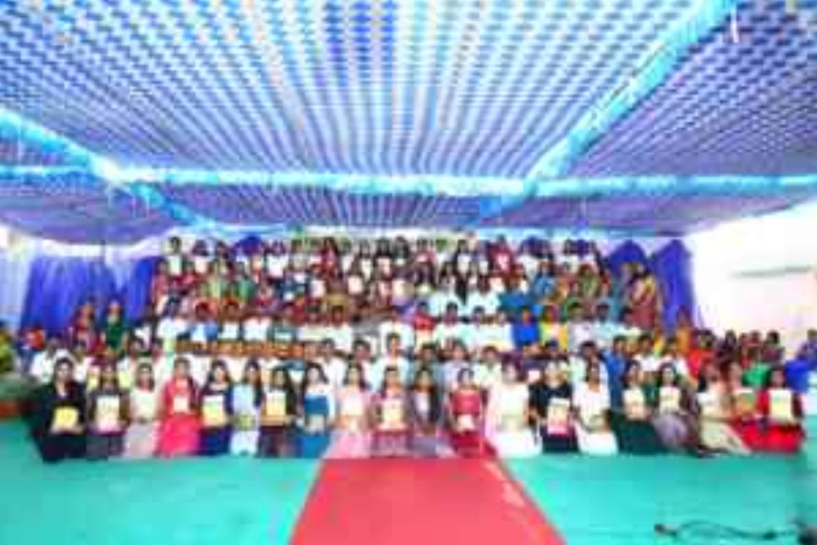 A packed auditorium of students seated for a stage event, with an illuminated "Apollo Public School" backdrop