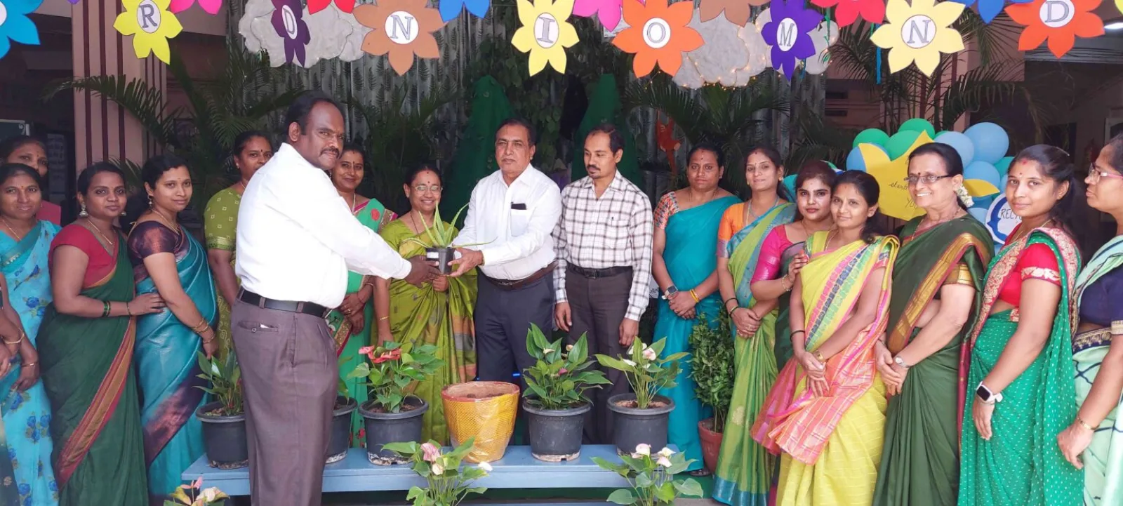 School management presenting a token of appreciation to a guest, surrounded by staff