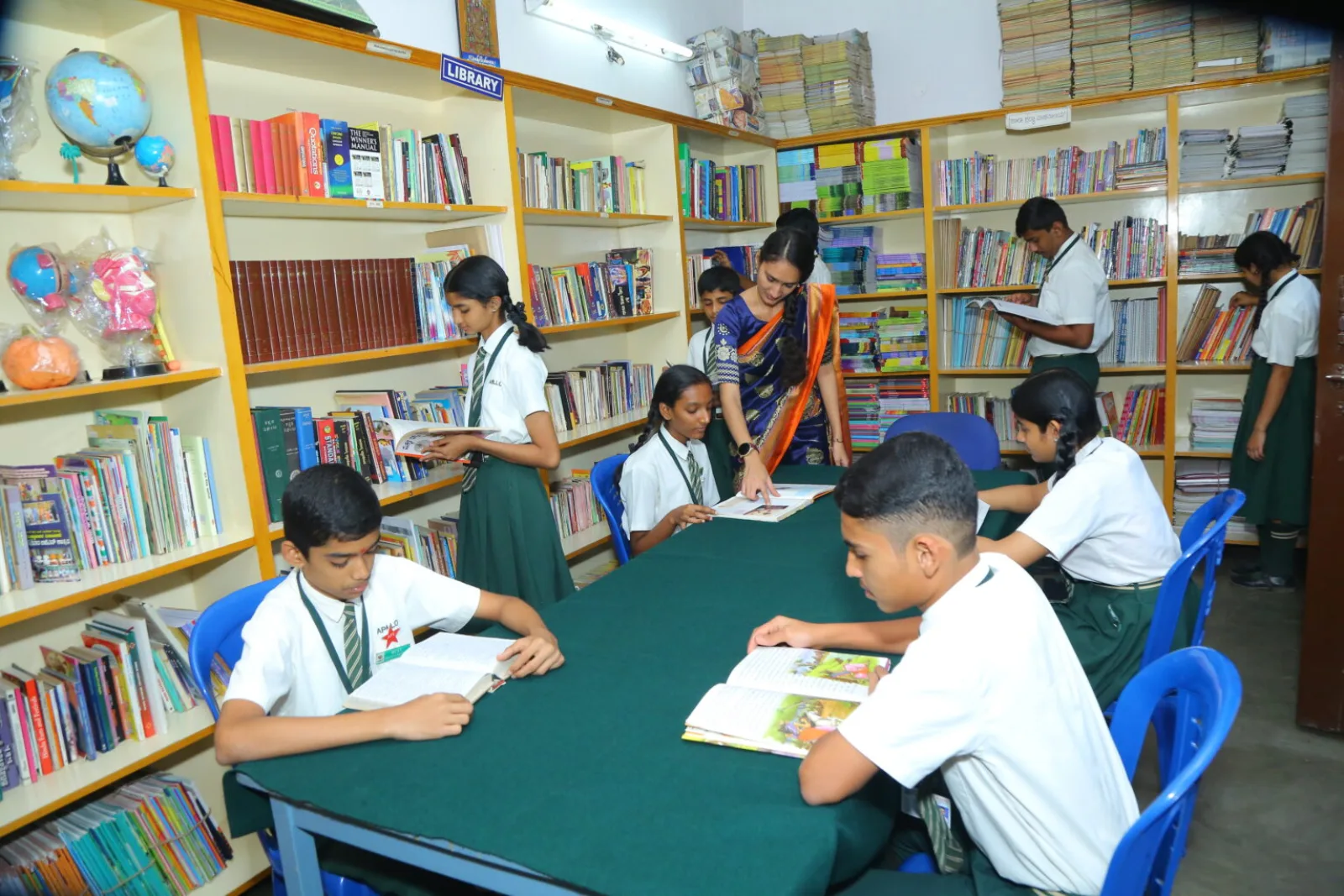Students reading and browsing books together on shelves in the school library