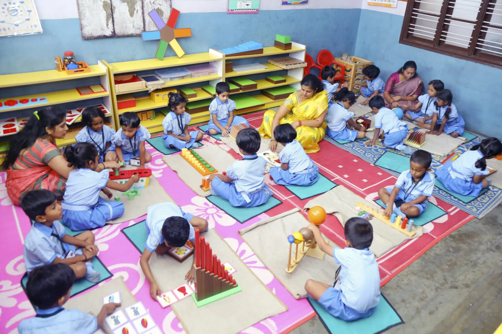 Young children seated on a colourful mat engaged in hands-on Montessori learning materials