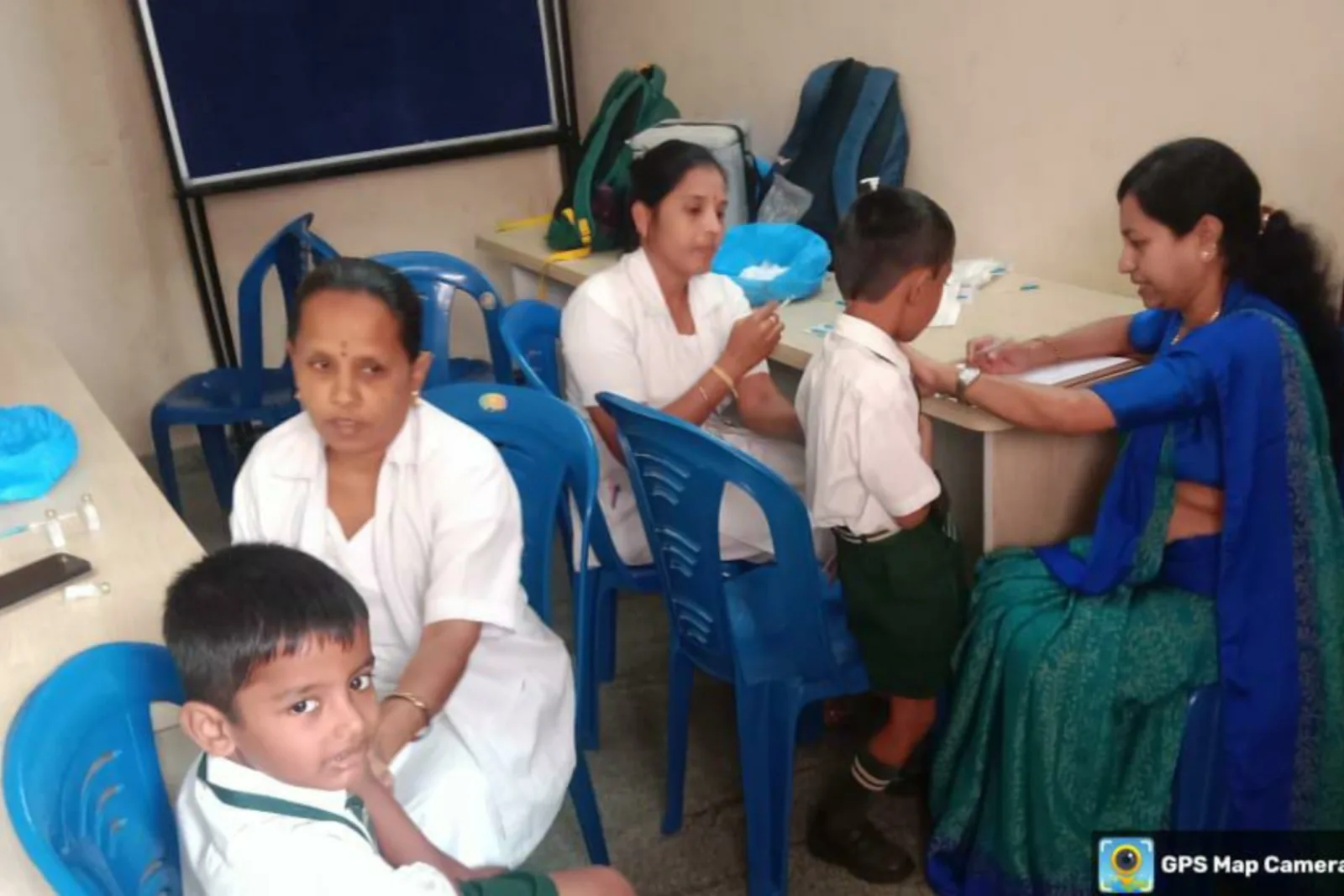A student having a health check-up performed by medical staff while classmates look on
