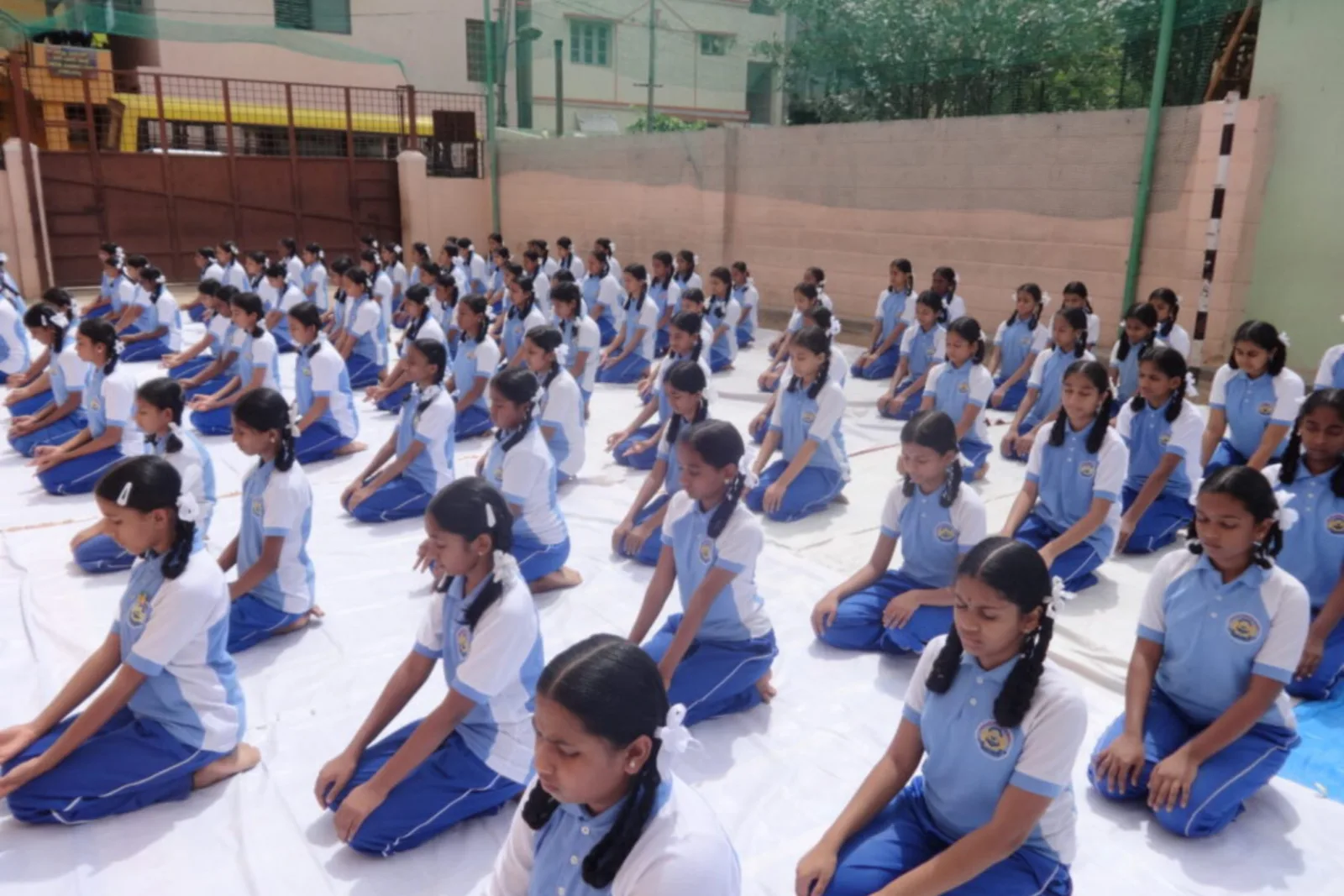 A large group of students sitting cross-legged with eyes closed for a meditation session