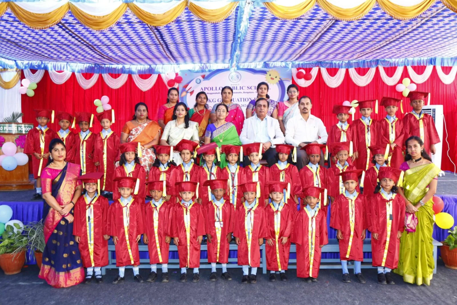 Wide view of a school event on the decorated stage with staff and students